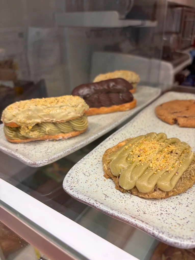 Vitrine com éclair de pistache, éclair de chocolate e cookie de pistache