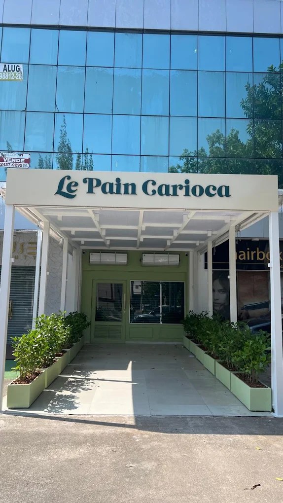 Fachada da Le Pain Carioca com toldo branco, porta verde e floreiras