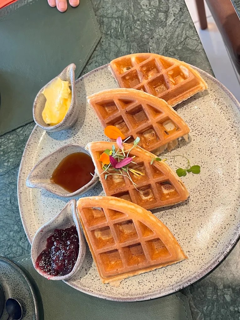 Waffle servido com manteiga, mel e geleia de frutas vermelhas
